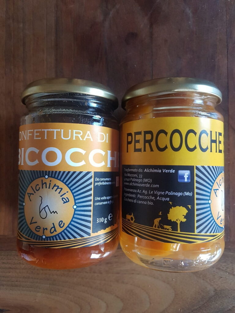 Vasetti di confettura artigianale di piccoli frutti aperto su un tavolo di legno con mirtilli e lamponi freschi dell'Appennino.